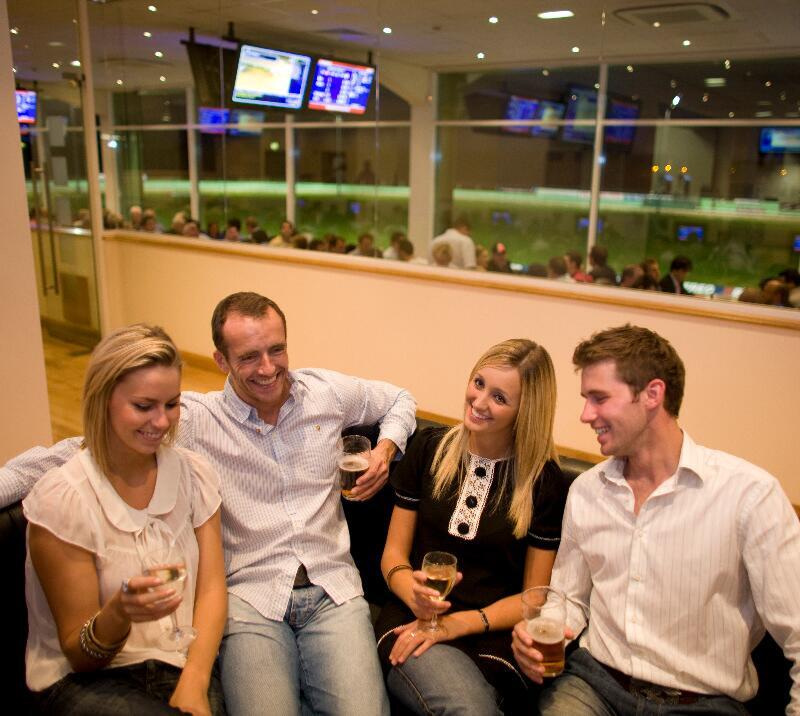 Group of 4 people sitting inside a greyhound stadium restaurant.